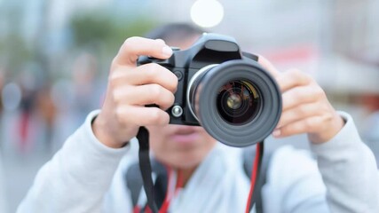 Photographer capturing images with the camera lens facing straight ahead, against the backdrop of a bustling city street illuminated by bokeh lights
