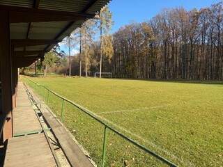 Obraz premium An empty rural football field in Betliar Slovakia with green grass a goalpost and woods in the background on a sunny autumn day