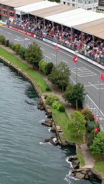 High angle vertical shot of a famous motorsport race track by the water with spectators in the grandstand.