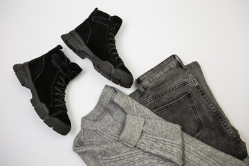 A harmonious combination of black boots, gray jeans, and a sweater, perfect for cold weather
