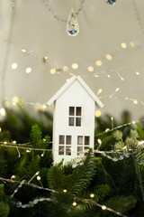 White decorative house with fairy lights and fir branches