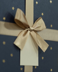 Close up of elegant gift box with golden ribbon and tag