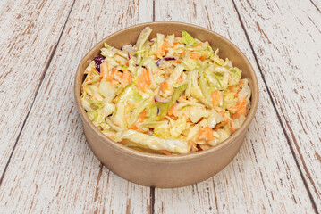 a delicious salad in a circular cardboard bowl