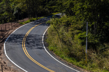 Fototapeta premium View of an empty paved rural road, flanked by Atlantic forest and eucalyptus fields in a mountain range in Brazil