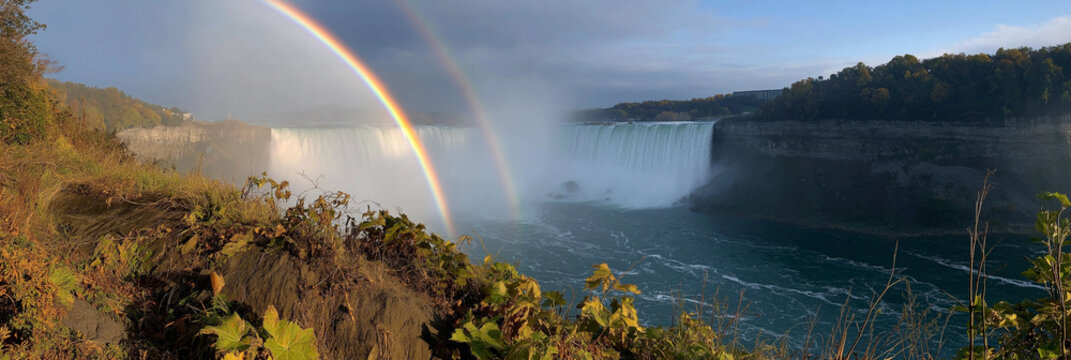 A stunning view of Niagara Falls encompassing a breathtaking double rainbow against the cascading waters, symbolizing nature's power and beauty.