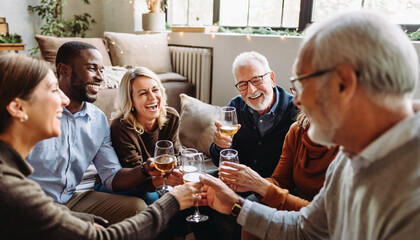 Happy group of adults enjoying New Year celebration at home, laughing and toasting with wine in cozy living room, festive atmosphere, diverse friends, casual clothing, natural light