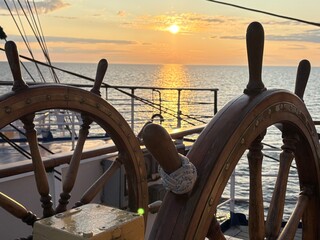 beautiful sunset at sea and an old ship's wheel