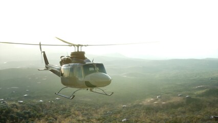 A helicopter soars through the sky above a vibrant green valley as the sun sets, casting a warm golden glow over the landscape. Tranquility meets adventure in this breathtaking moment. © icetray