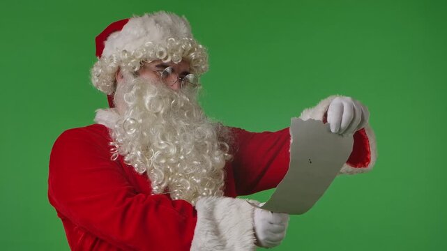 Santa Claus reading a letter on a green chroma key background. Ideal for Christmas themed compositions.