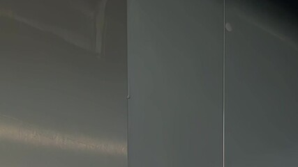 A person, dressed in whites, cleans a stainless steel wall, wiping it down with a damp cloth in a commercial kitchen setting during the early morning.