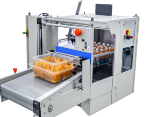 A machine moves a plastic tray of orange food on a conveyor belt for processing in its automated system