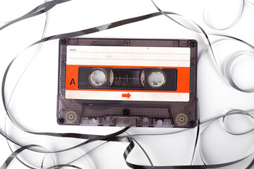 Music sound and mental health Concept. Old transparent compact. Vintage Audio cassette tape with exposed film composition unwound in mess on white background.