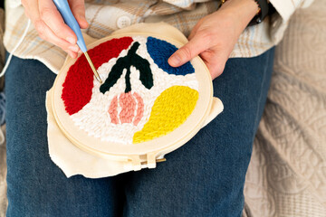 Crafting colorful patterns with yarn for a unique textile art piece in a cozy indoor setting