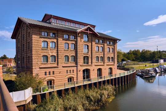Renovated historic harbor warehouse Hafenspeicher stands prominently by the Stepenitz River in Dassow, Germany, marking the town entrance with classic brick architecture and waterfront heritage charm