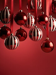 Red and white solid and striped Christmas ornaments against gradient red background. Space for text.