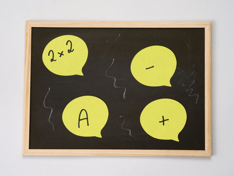 Small school blackboard with chalk and yellow sticky notes with letters and numbers