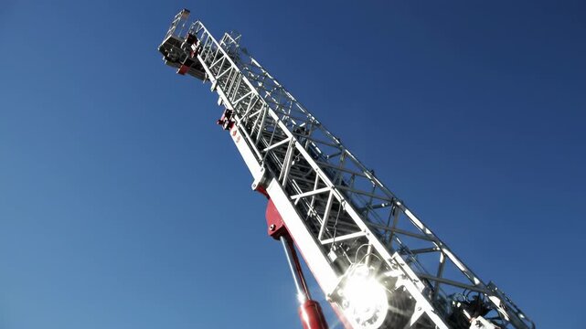 Modern Fire Truck Ladder Extended Against Blue Sky on a Bright Sunny Day