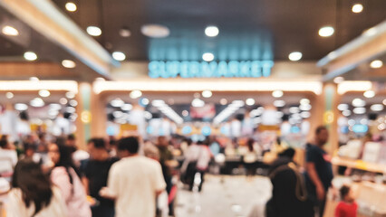 blurry image of a busy interior of a supermarket, the ambiance showing the self-service model in action with numerous people shopping in the aisles.