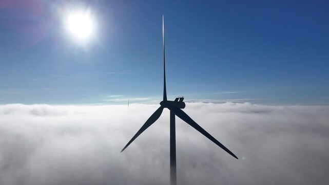 Une &eacute;olienne &eacute;merge au dessus d'un banc de brouillard, au mois de novembre, en automne, sur un beau ciel bleu. Parc &eacute;olien de Doncourt-les-Longuyon, en Meurthe et Moselle, Lorraine.