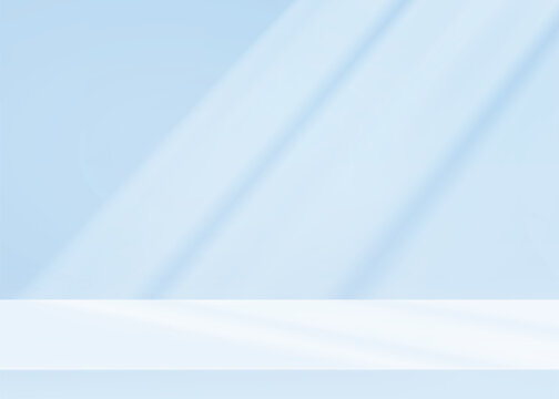 Empty studio background in soft blue tones with natural sunlight and window shadow patterns on wall. Minimalist limbo setup for product photography or presentation backdrop layouts.