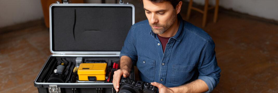 A focused man meticulously organizes his camera gear, demonstrating the preparation process essential to photography, highlighting dedication and the importance of equipment in capturing moments.