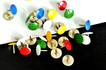 A pile of paper pushpins on a black and white background.