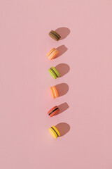 Colorful macarons on pastel pink background. Minimal sweet food concept. Trendy pastel colors idea. Flat lay style. Top view. Macarons aesthetic.