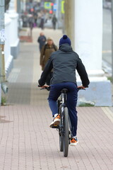 A man rides a bicycle on the sidewalk