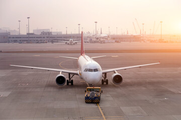 An airplane is positioned on the tarmac, getting ready for takeoff as the sun sets in the...