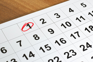 Number 1 marked in the calendar with red color circle to point important date on the wooden table