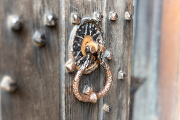 Rustic metal door knocker on old wooden door