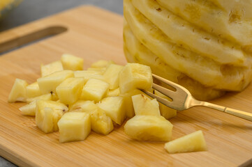 Real ripe pineapple cut into cubes, tasty snack, tropical fruit sweet and sour snack, yellow inside