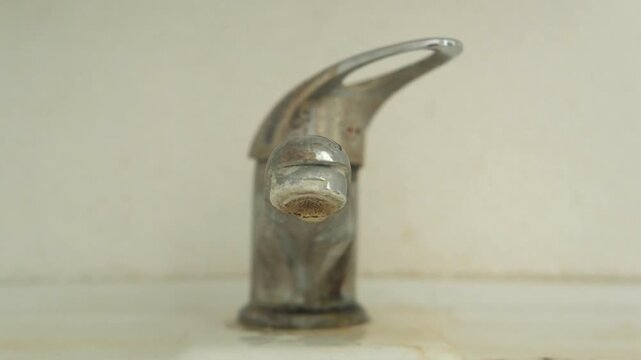 An old, dirty, hard water scaled, dripping or leaking faucet