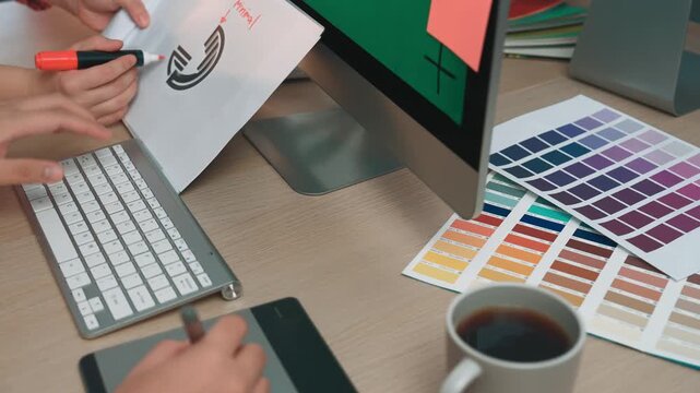 A creative workspace featuring a modern computer with colorful design elements and swatches. Hands engaged in digital design, coffee cup nearby, fostering inspiration. SACTR