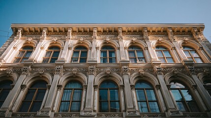 Obraz premium Detailed facade with arched windows and ornate carvings on a historical building under a bright blue sky. A timeless architectural masterpiece. #architecture #windows
