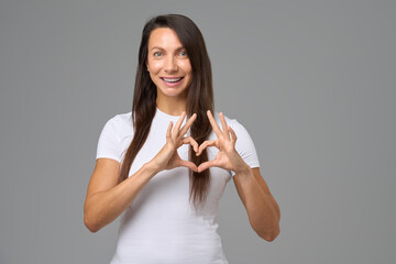 Smiling woman making a heart shape with fingers expressing happiness and love