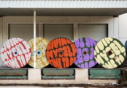 Colorful Wooden Spools Lined up Against a Building in Broad Daylight