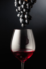 Red wine and bunch of blue grapes.