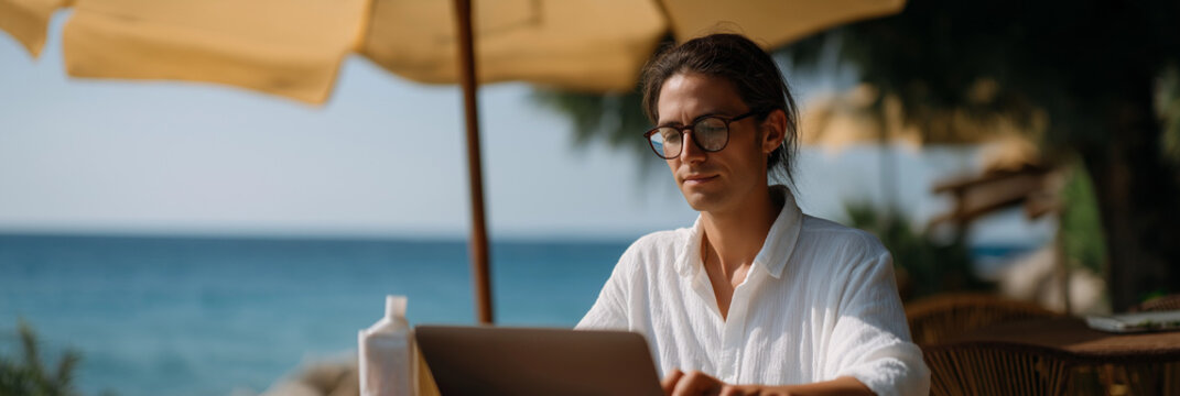 A young woman peacefully works on her laptop by the seaside, embodying the modern concept of remote work and the beauty of balancing career with the tranquility of nature.