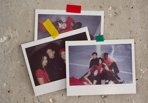 Three blank polaroids templates resting against a textured surface with colorful tape holding them in place