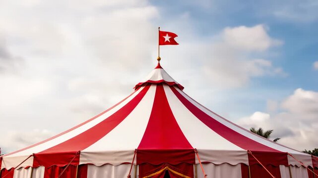 Red and White Circus Tent - This video showcases the top of a classic circus tent, featuring red and white stripes. A small red flag with a white star flies proudly atop the tent against a cloudy sky.