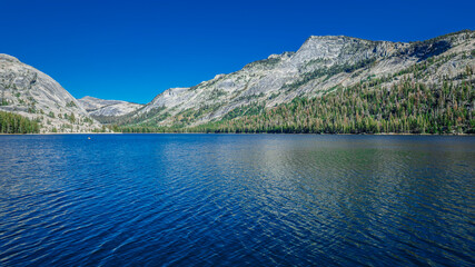 Aerial view of stunning alpine lake nestled amongst granite peaks. Clear blue water reflects...