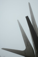 Minimalist composition showing the pointed shapes of the Kosmaj Monument disappearing into thick fog
