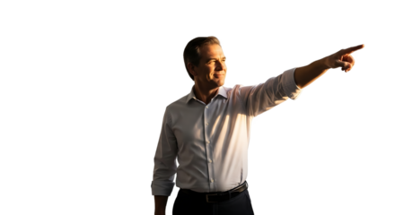 A confident businessman in a light blue dress shirt points his finger to the right while standing against a dark isolated background during the golden hour sunlight