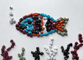 Mosaic, background. A fish made of colored sea pebbles candies on a textile background.