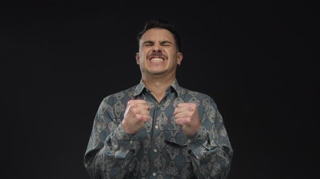 Young man expressing emotion against an isolated black background wall wearing a patterned shirt in various moods conveying dynamic expression and style
