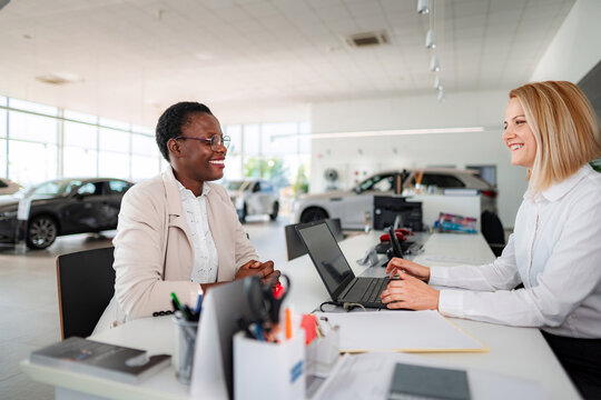 Diverse women discussing car purchase at dealership desk