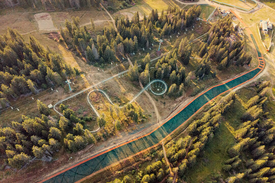 Vibrant summer scene capturing a mountain bike park featuring a chairlift, winding trails, and lush forests from an aerial perspective