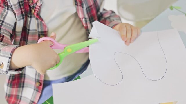 Child's hands cutting paper with scissors