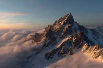 Majestic snow-capped mountain peaks illuminated by sunset over a valley with soft clouds